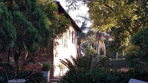 Ein Garten mit Brunnen, Bank und einem Backsteinhaus.