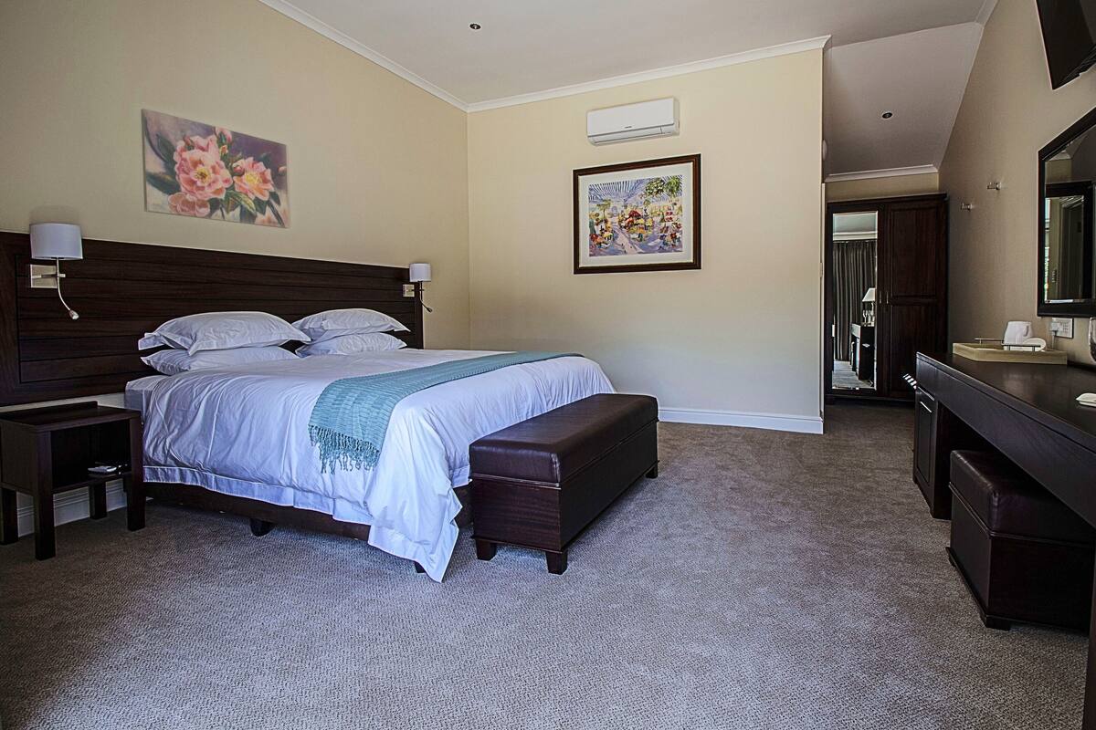 A hotel room with a large bed, a bedside table, a dresser, and a mirror.