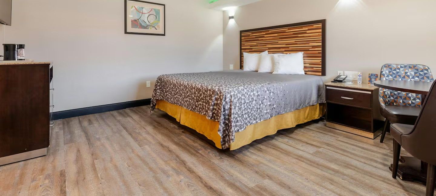 Een hotelkamer met een bed, een bureau, een stoel, een dressoir en een kunstwerk aan de muur.