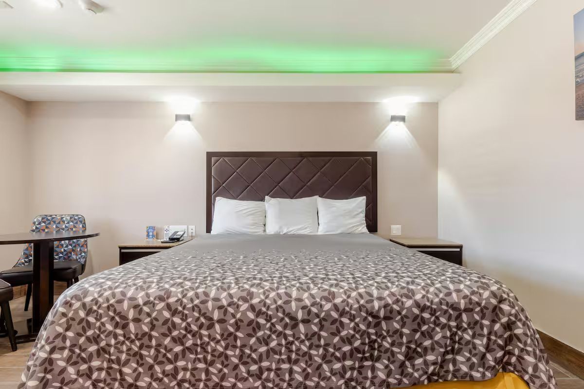 Hotellihuone, jossa on sänky, yöpöydät, työpöytä ja tuoli.