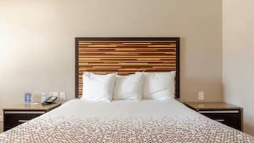 A hotel room with a bed, a bedside table, a nightstand, and a wall-mounted telephone.