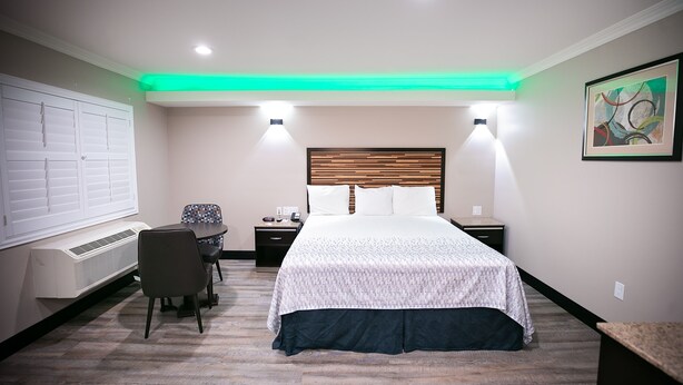 A hotel room with a bed, bedside tables, a desk, and a chair.