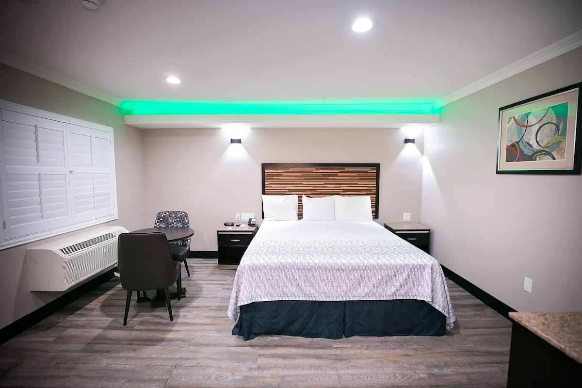 Une chambre d’hôtel avec un lit, des tables de chevet, un bureau et une chaise.