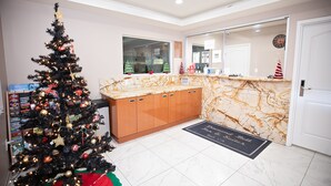 A hotel lobby with a Christmas tree, marble reception desk, and a door to the right.