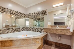 Une salle de bain moderne avec une grande baignoire, un meuble-lavabo avec un miroir et un sèche-cheveux fixé au mur.