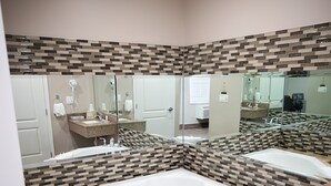 A modern bathroom with a large bathtub, two sinks, and a mirror.