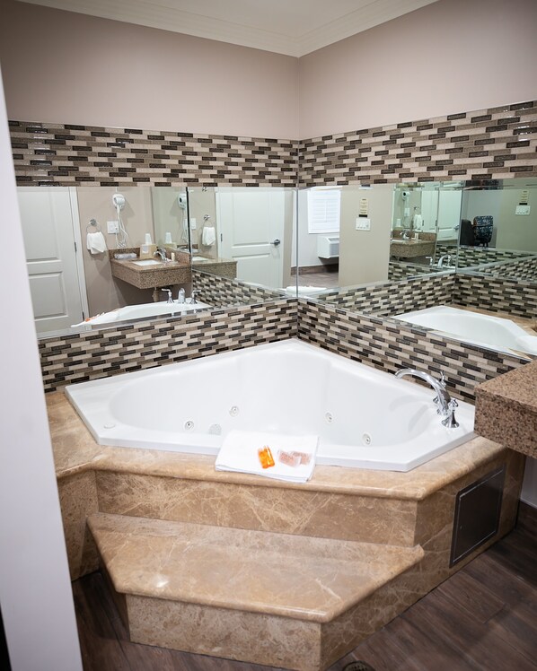 A modern bathroom with a large bathtub, two sinks, and a mirror. - Diamond Bell Inn & Suites (Bell Gardens)