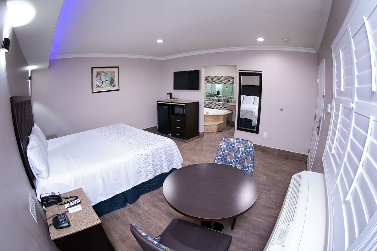 Une chambre d’hôtel comprenant un lit, un bureau avec un téléphone, une chaise, une table, un miroir, un téléviseur et un radiateur.