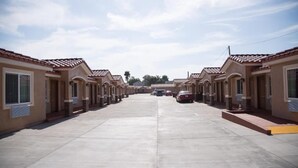 A row of single-story buildings with a uniform architectural style, featuring a tiled roof and a central courtyard.