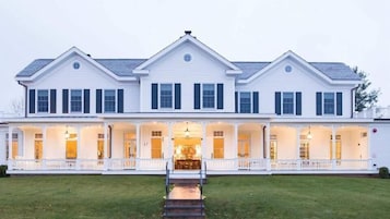 A large, two-story white building with a covered front porch and multiple windows.