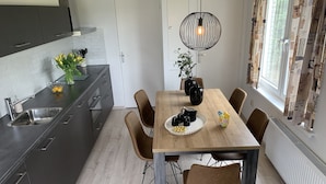 A modern kitchen with dark cabinets, a wooden dining table, and a hanging light fixture.