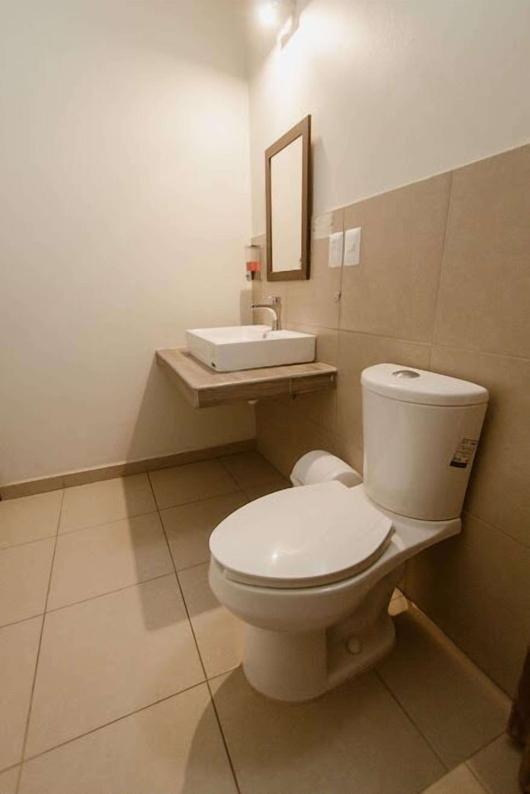 A small, clean bathroom with a toilet, sink, and mirror.