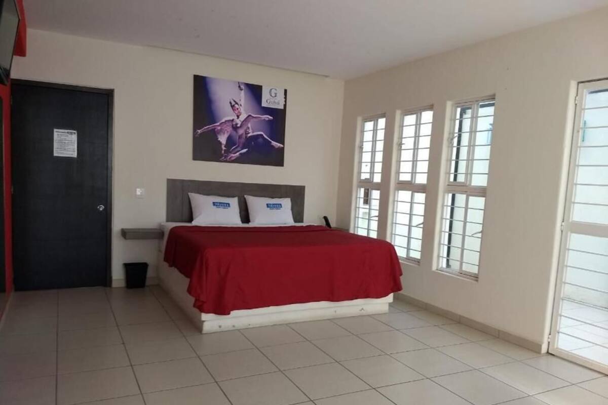 Ein Schlafzimmer mit Bett, Nachttisch, einem an der Wand hängenden Poster und einem Fenster mit Blick.