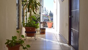 A hallway with potted plants, a dark door, and a tiled floor. - Hotel Guivá San Pablo (Oaxaca)