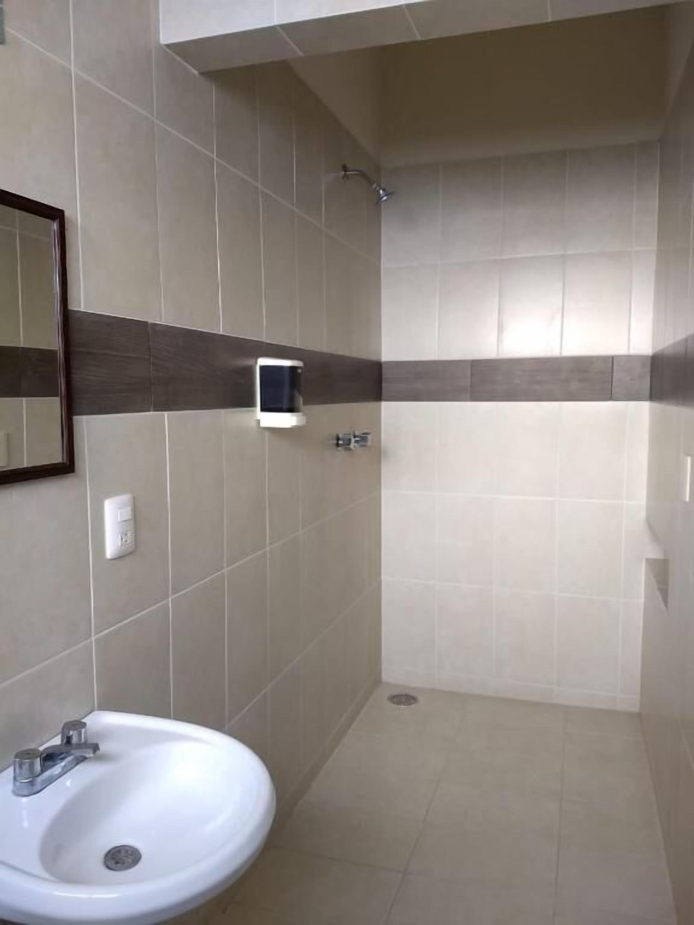 Un baño con lavamanos, espejo y ducha.