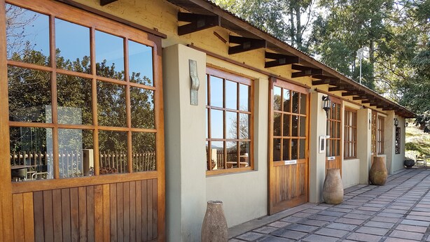 A building with large wooden-framed windows and a tiled walkway. - Misty Mountains (Studholme)