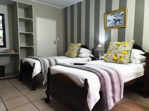 A bedroom with two beds, striped walls, a door, a shelf with books, and a framed picture on the wall. - Misty Mountains (Studholme)