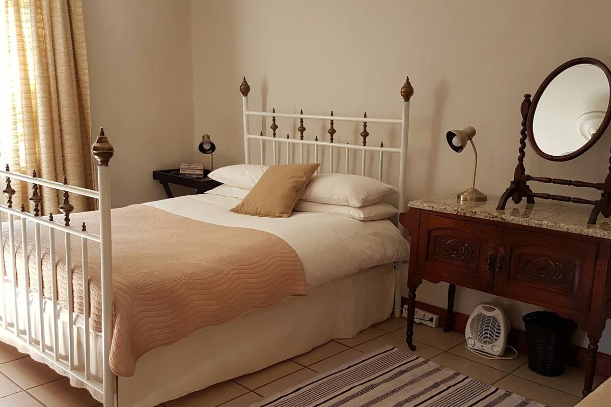 A bedroom with a bed, nightstands, a dresser, a mirror, and a radiator.