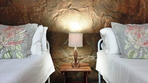 A room with two beds, a nightstand with a lamp, and a textured wall. - Misty Mountains (Studholme)