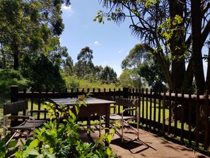 An outdoor seating area with a table and chairs, surrounded by a wooden fence and lush greenery. - Misty Mountains (Studholme)