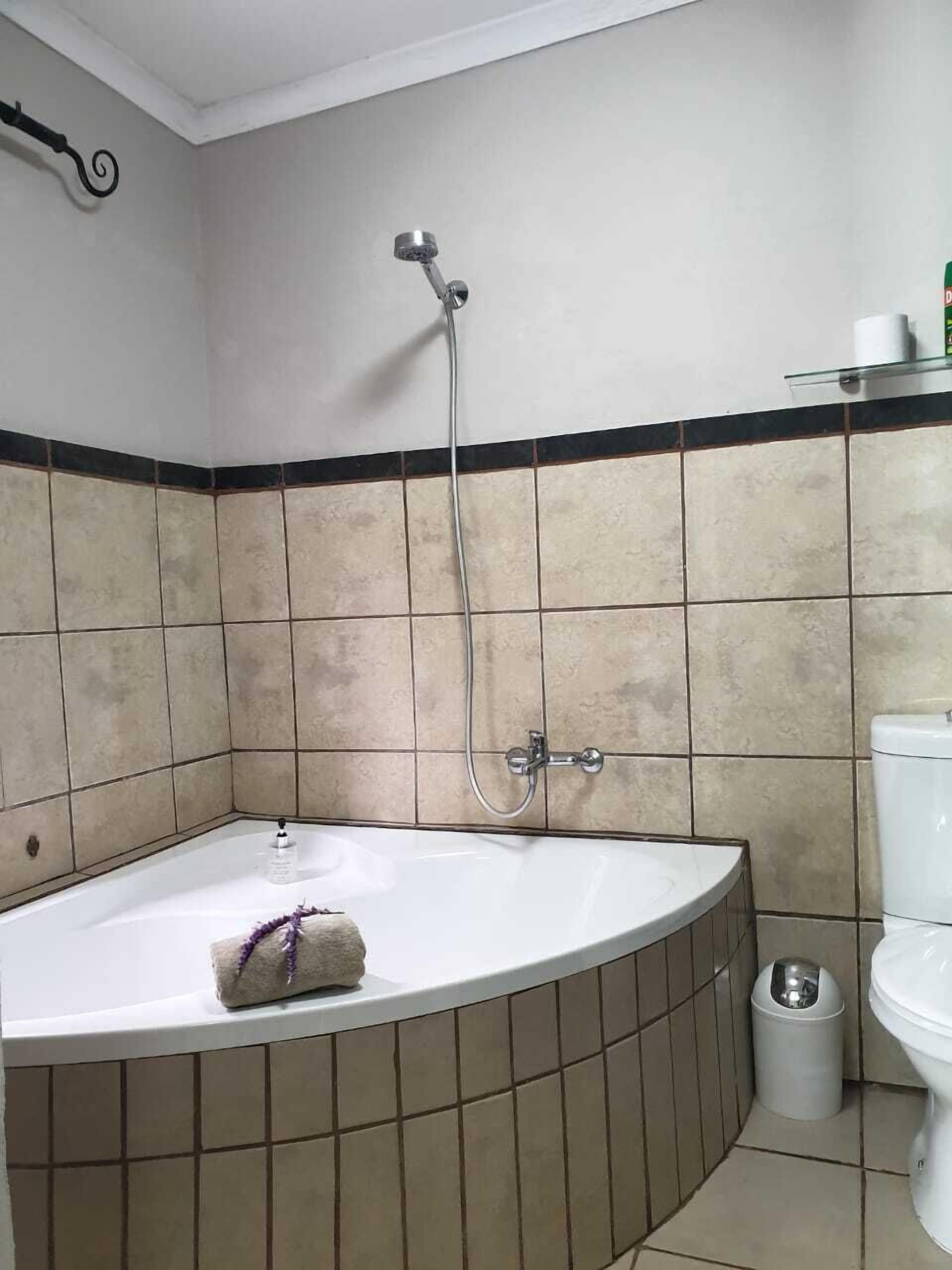 A bathroom with a bathtub, a toilet, and a trash bin.