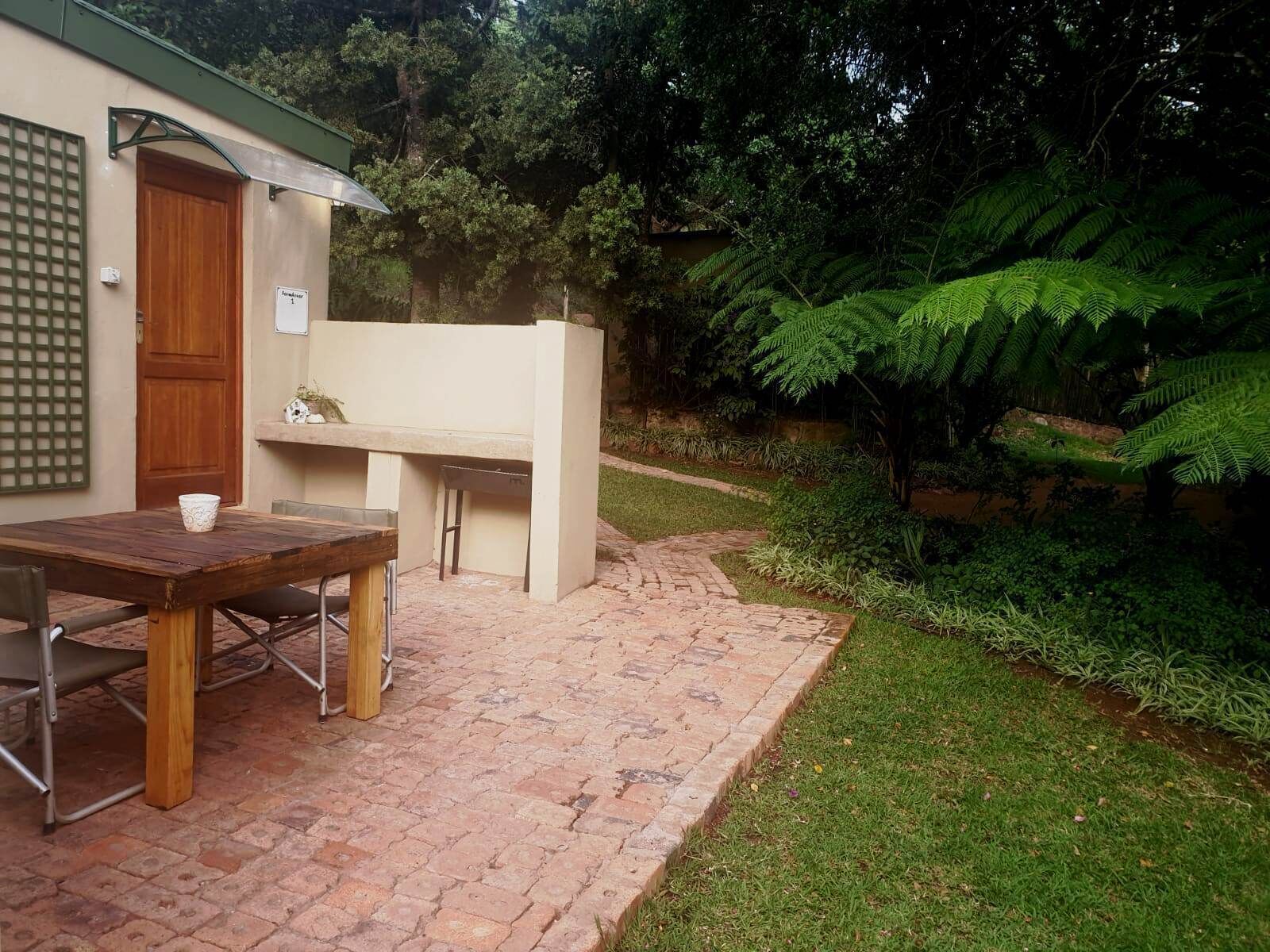 A patio with a table and chairs, a wooden door, and a small outdoor kitchen area.
