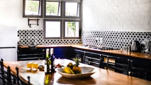 A kitchen with a white brick wall, black and white patterned backsplash, and a window with a view of trees. - Karoo Retreat (Oudtshoorn)