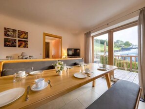 A dining area with a long table set for breakfast, a television, and artwork on the wall. - Spacious Stay with Mountain View (Wald-Königsleiten)