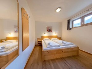 A bedroom with a wooden bed, two bedside tables, a mirror, and a window. - Spacious Stay with Mountain View (Wald-Königsleiten)