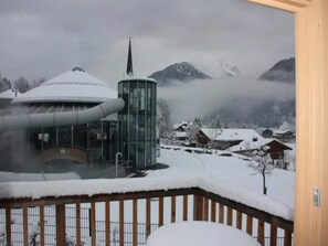 Un paysage montagneux enneigé, avec un bâtiment moderne doté d’une structure cylindrique et d’une flèche.