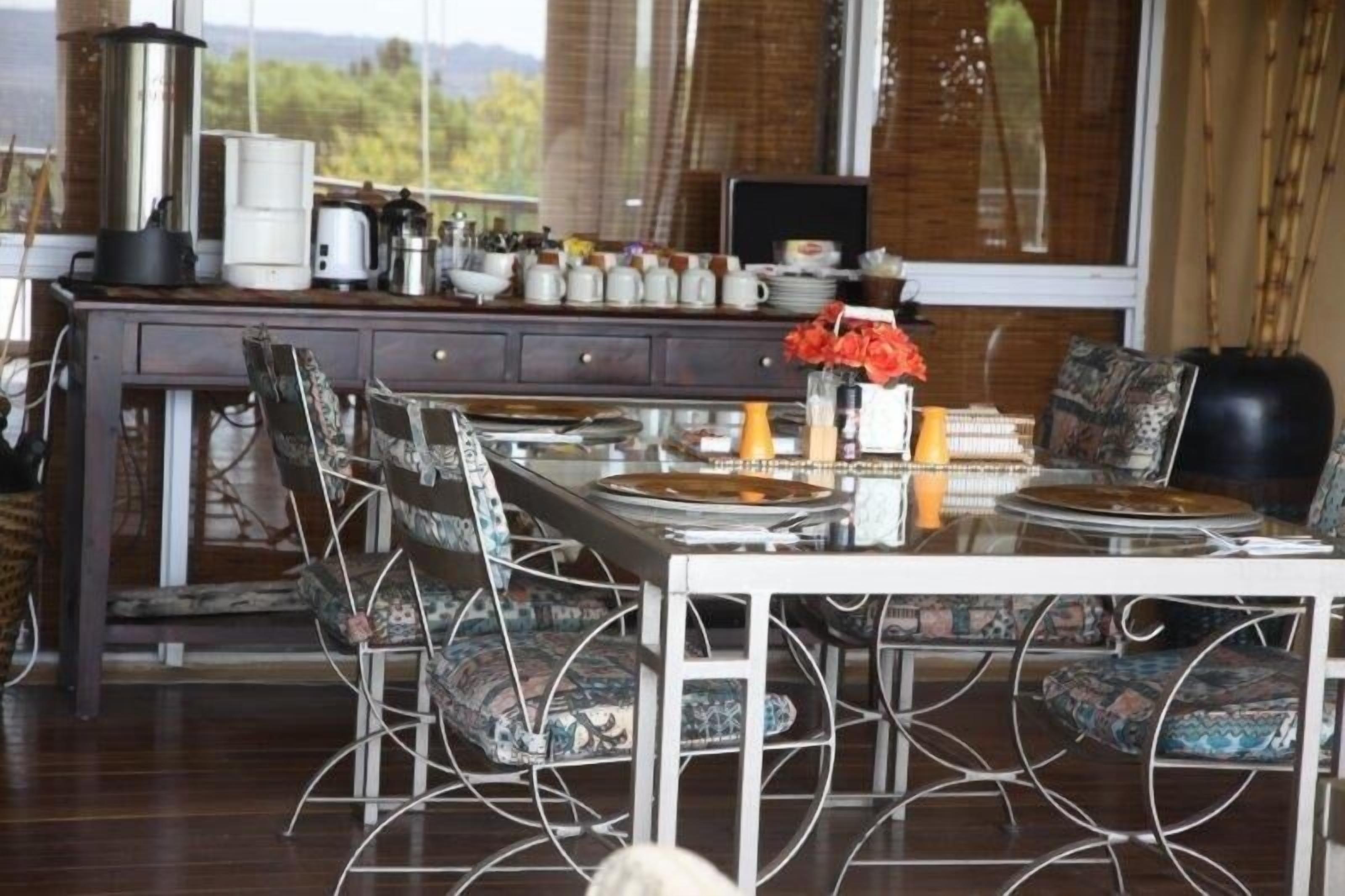 Un coin repas avec une table blanche, des chaises à motifs et divers appareils de cuisine disposés sur un comptoir en bois.