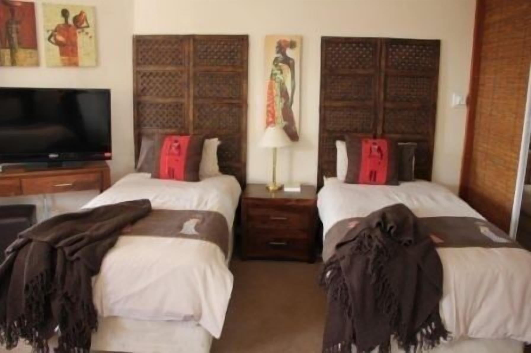 A hotel room with two beds, a television, and artwork on the walls.