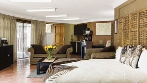 Ein Hotelzimmer mit einem großen Bett, zwei Sesseln, einem Schreibtisch und einem Fernseher.