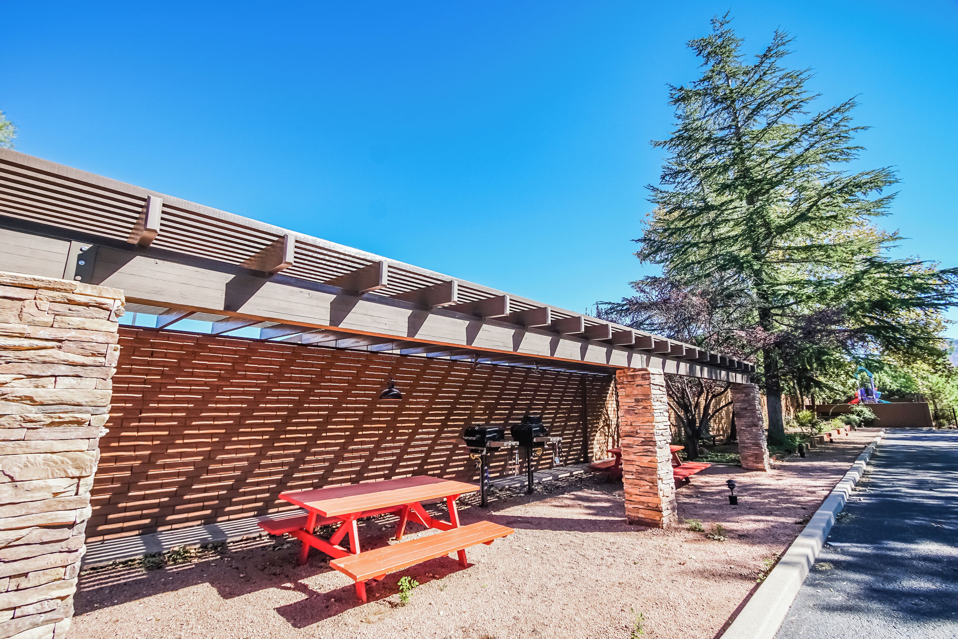 A covered outdoor seating area with a picnic table and grill.
