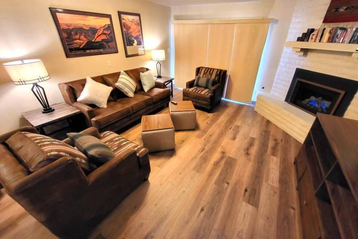 A living room with a brown leather sofa, a wooden coffee table, a striped armchair, and a fireplace.