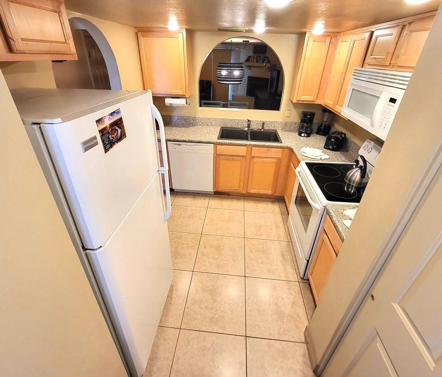 A compact kitchen with a refrigerator, dishwasher, microwave, and stove.