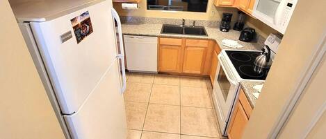A compact kitchen with a refrigerator, dishwasher, microwave, and stove.