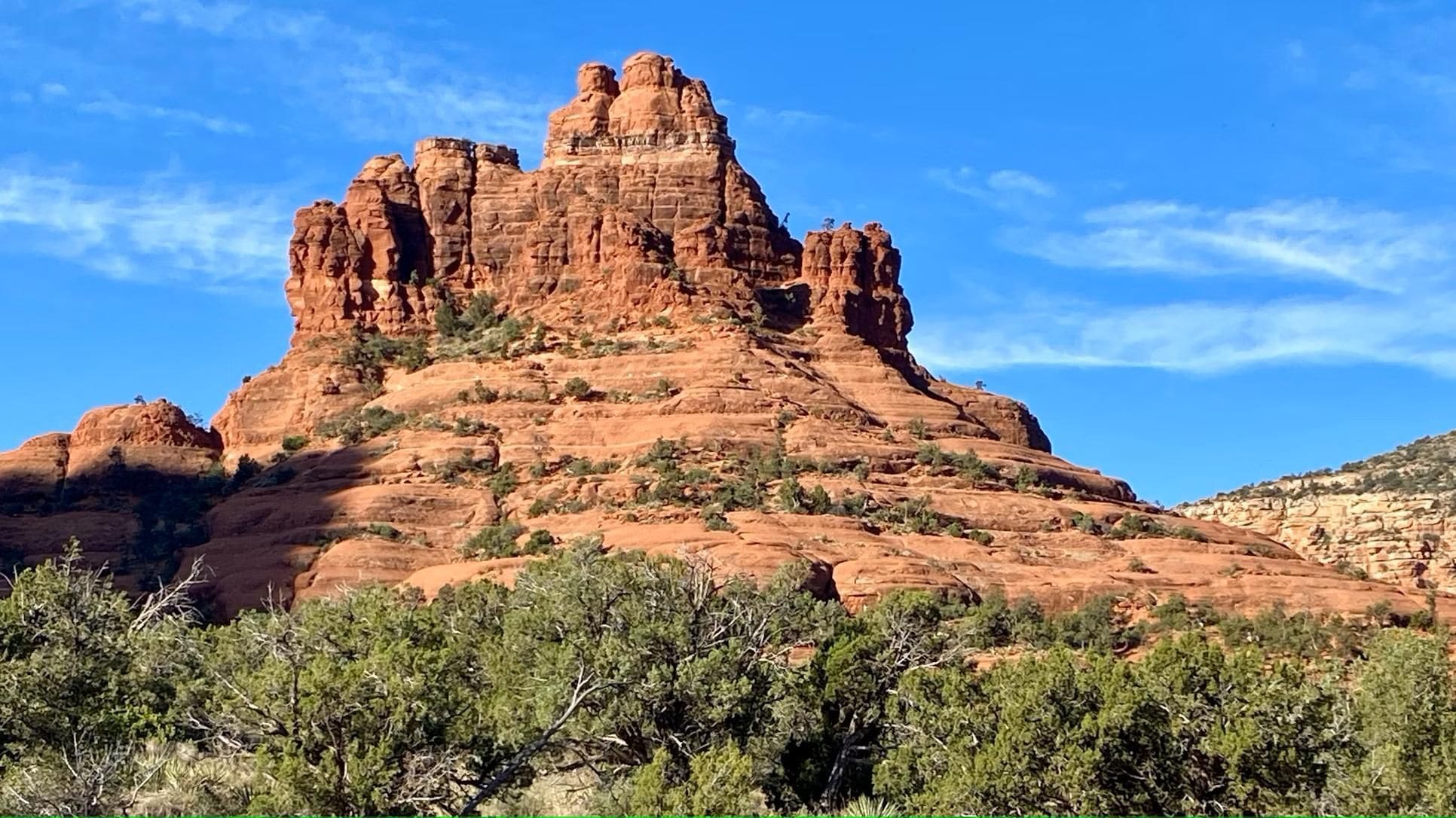 A large, red rock formation with a clear sky.