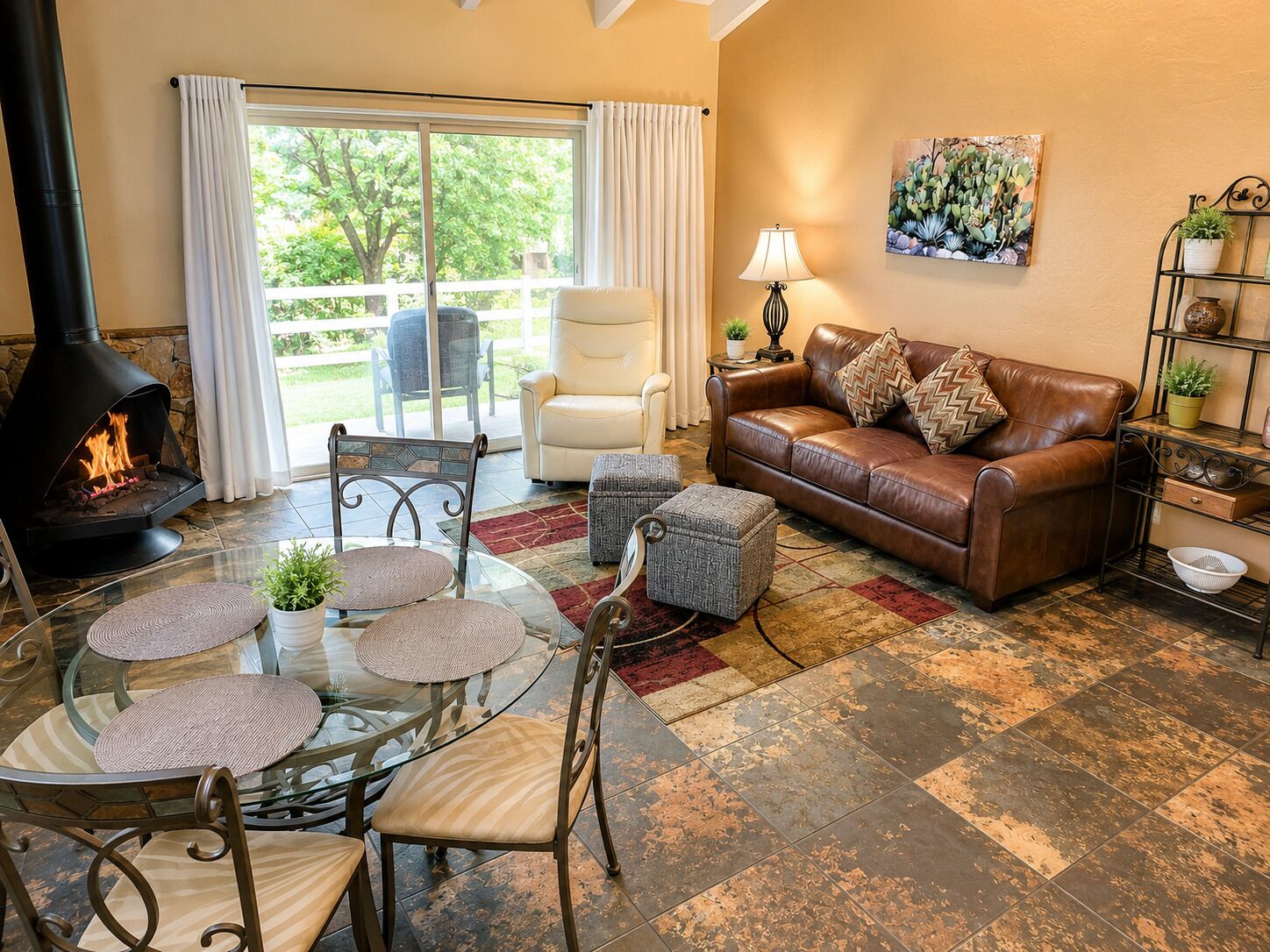 A cozy living room with a fireplace, a leather sofa, a glass coffee table, and a dining area with chairs.