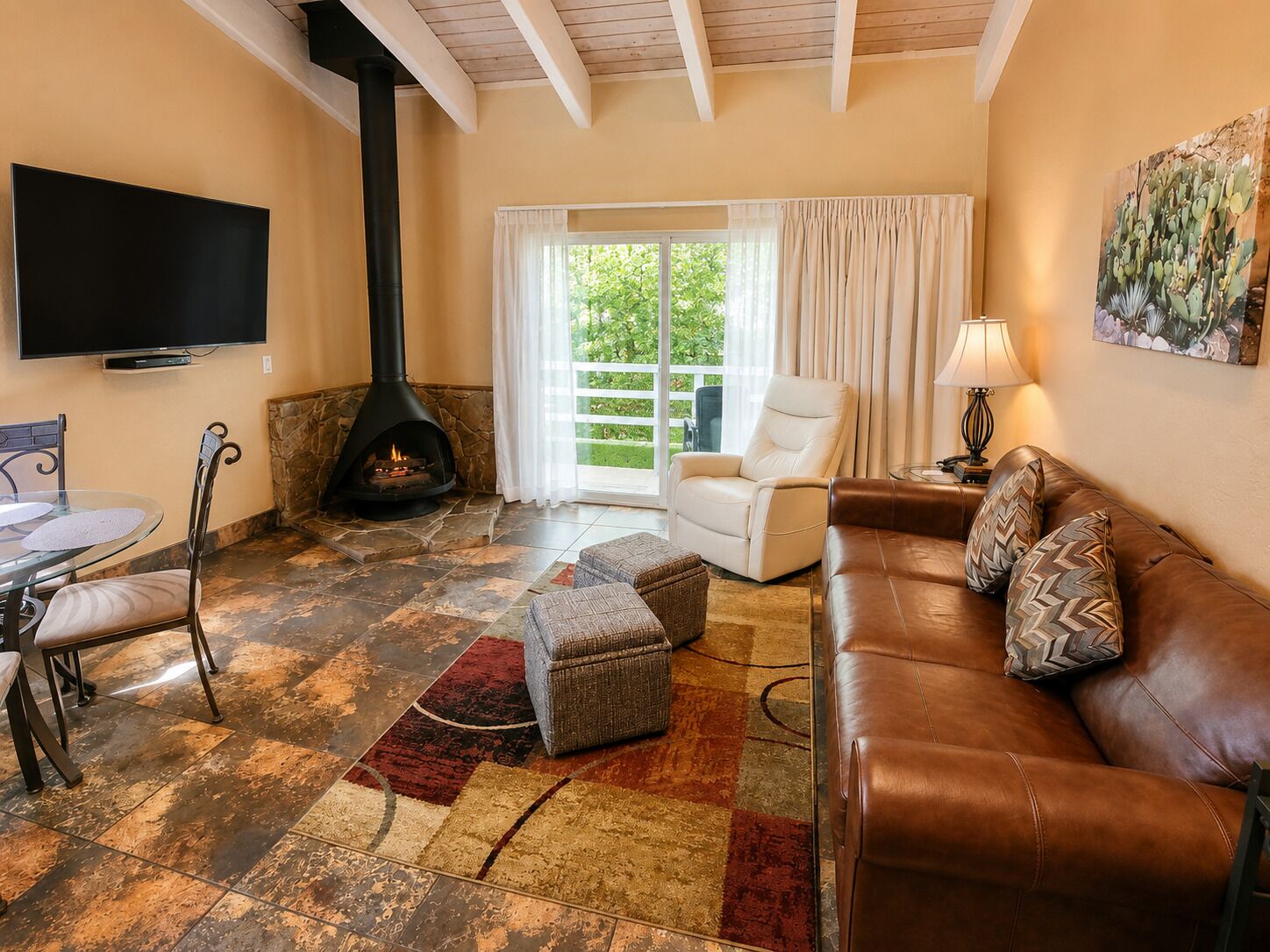 A living room with a fireplace, a sofa, a chair, a TV, and a large window.