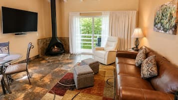 A living room with a fireplace, a sofa, a chair, a TV, and a large window.