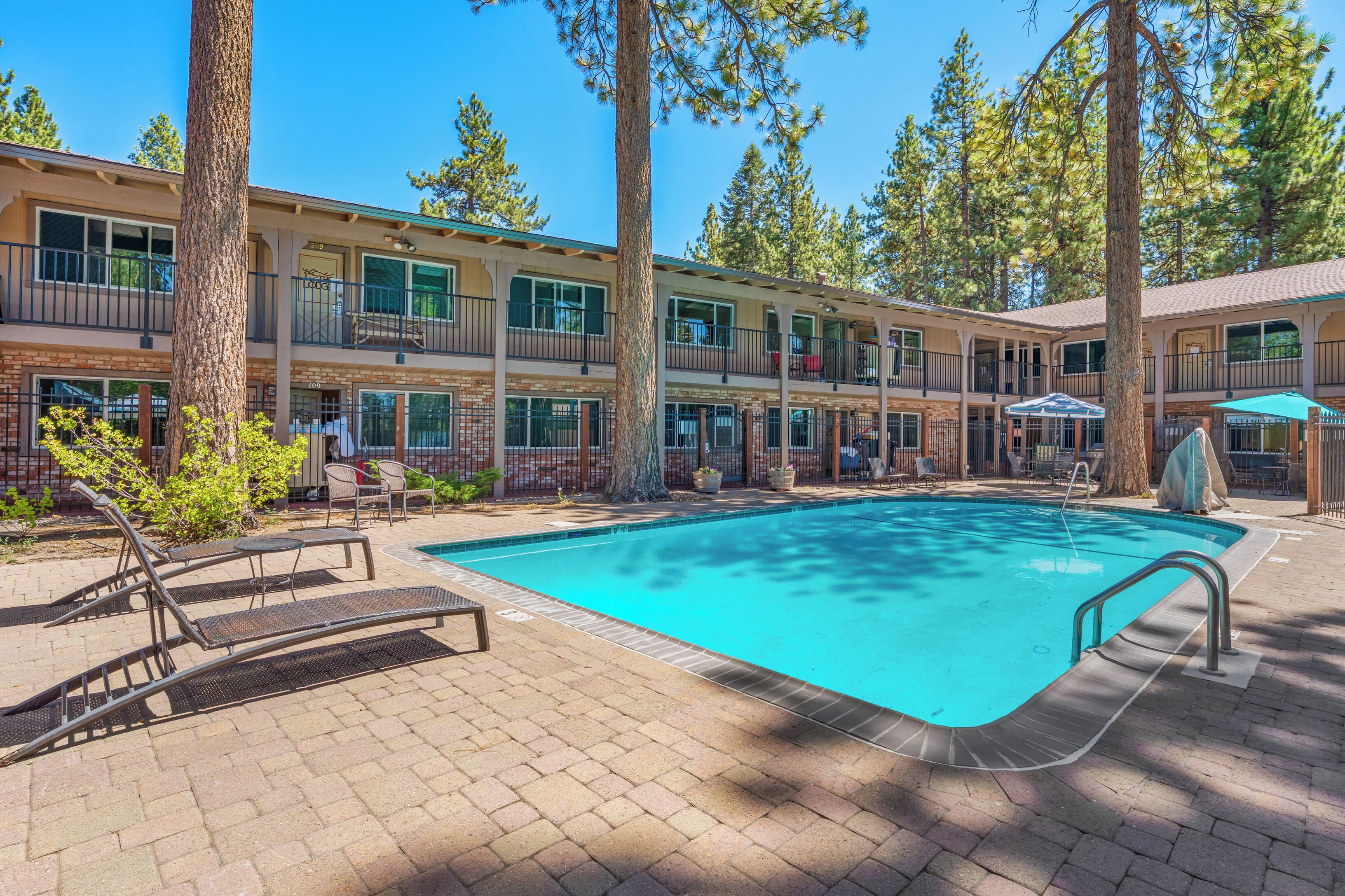 A pool area with lounge chairs, a pool, and a building with multiple balconies and windows.