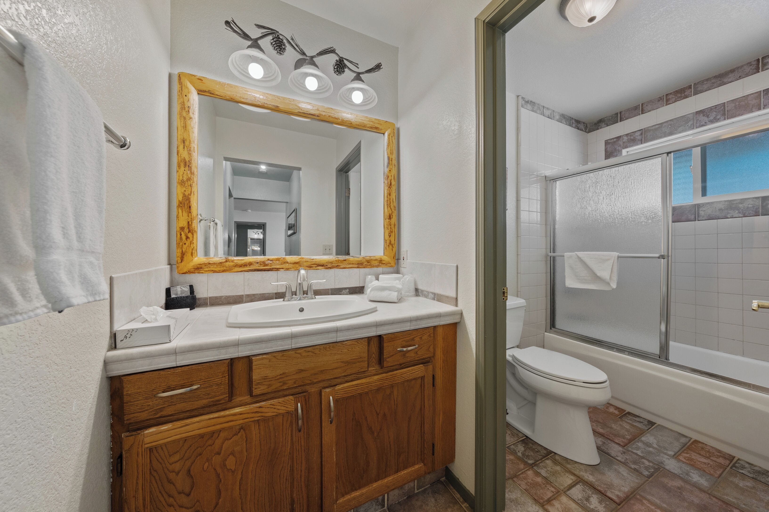 A bathroom with a wooden vanity, white sink, and a large mirror.