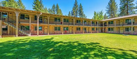 A motel with multiple floors, outdoor seating, and a well-maintained lawn.