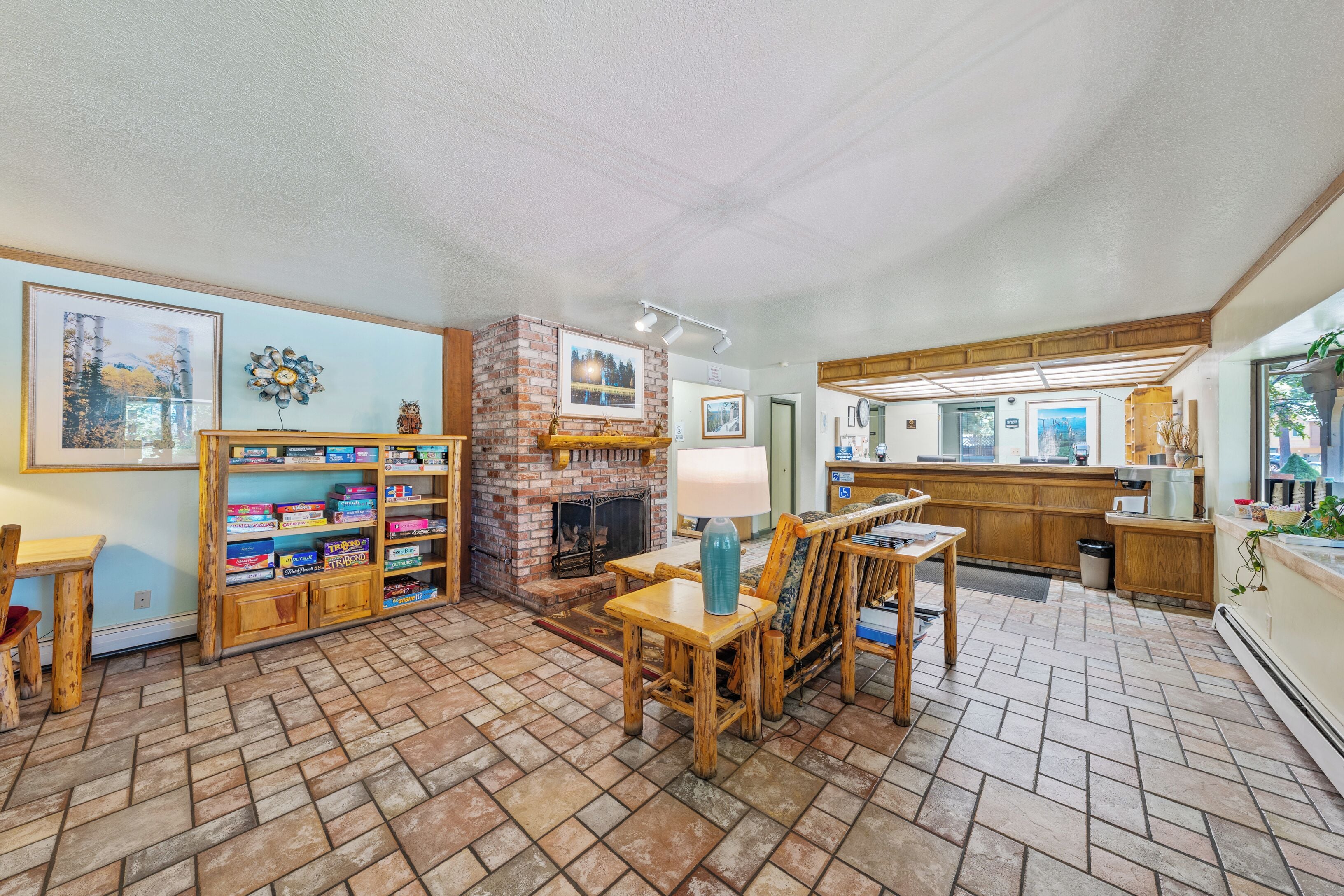 A cozy living area with a fireplace, wooden furniture, and a kitchen in the background.