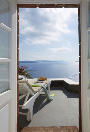 A view from a room with a white door leading to a balcony overlooking the sea. - Atrina Canava 1894 (Santorini)