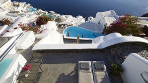 A rooftop pool area with white architecture, a clear view of the sea, and lounge chairs. - Atrina Canava 1894 (Santorini)