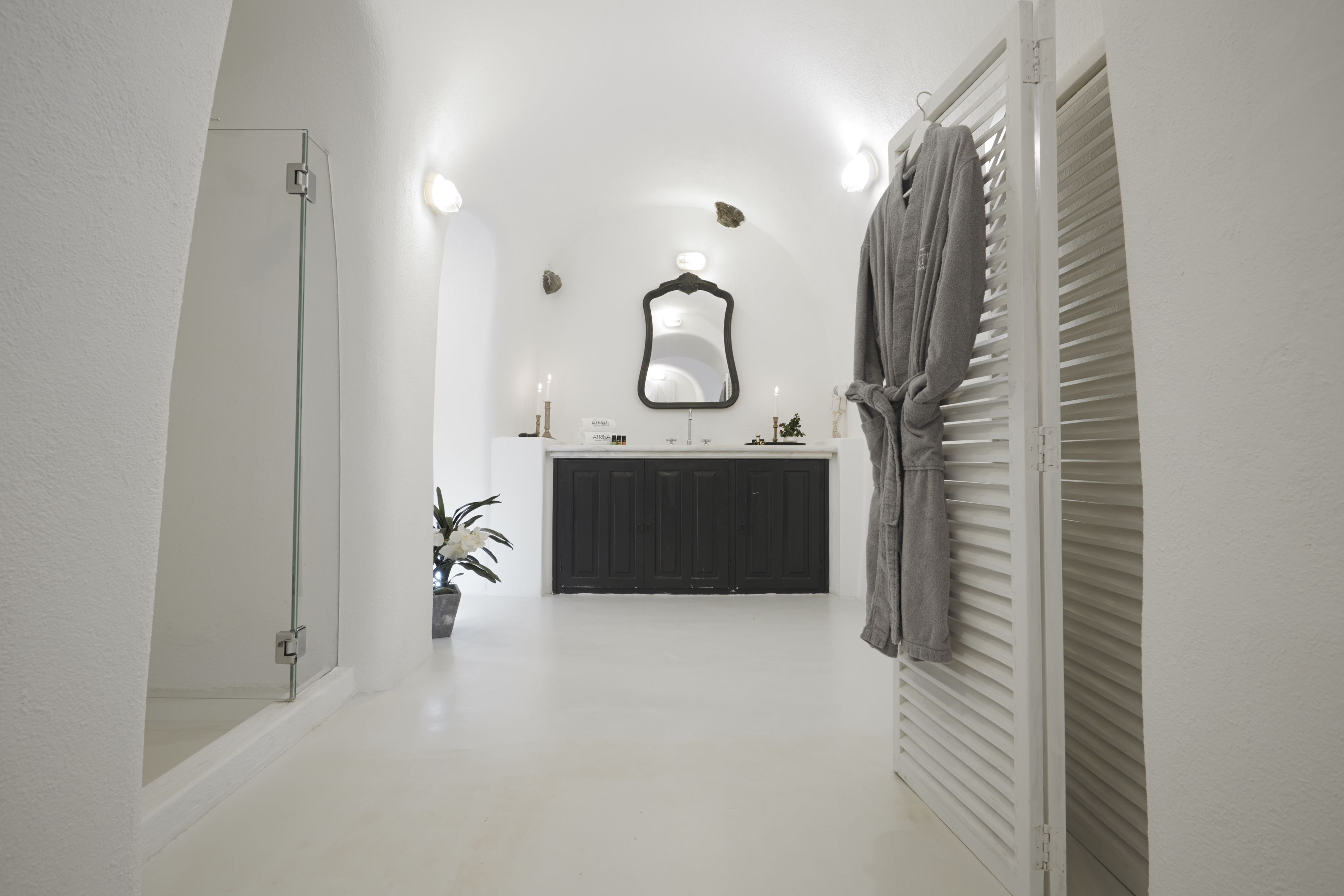 Un pasillo estrecho que lleva a un baño con un lavabo blanco, espejo y toallero.