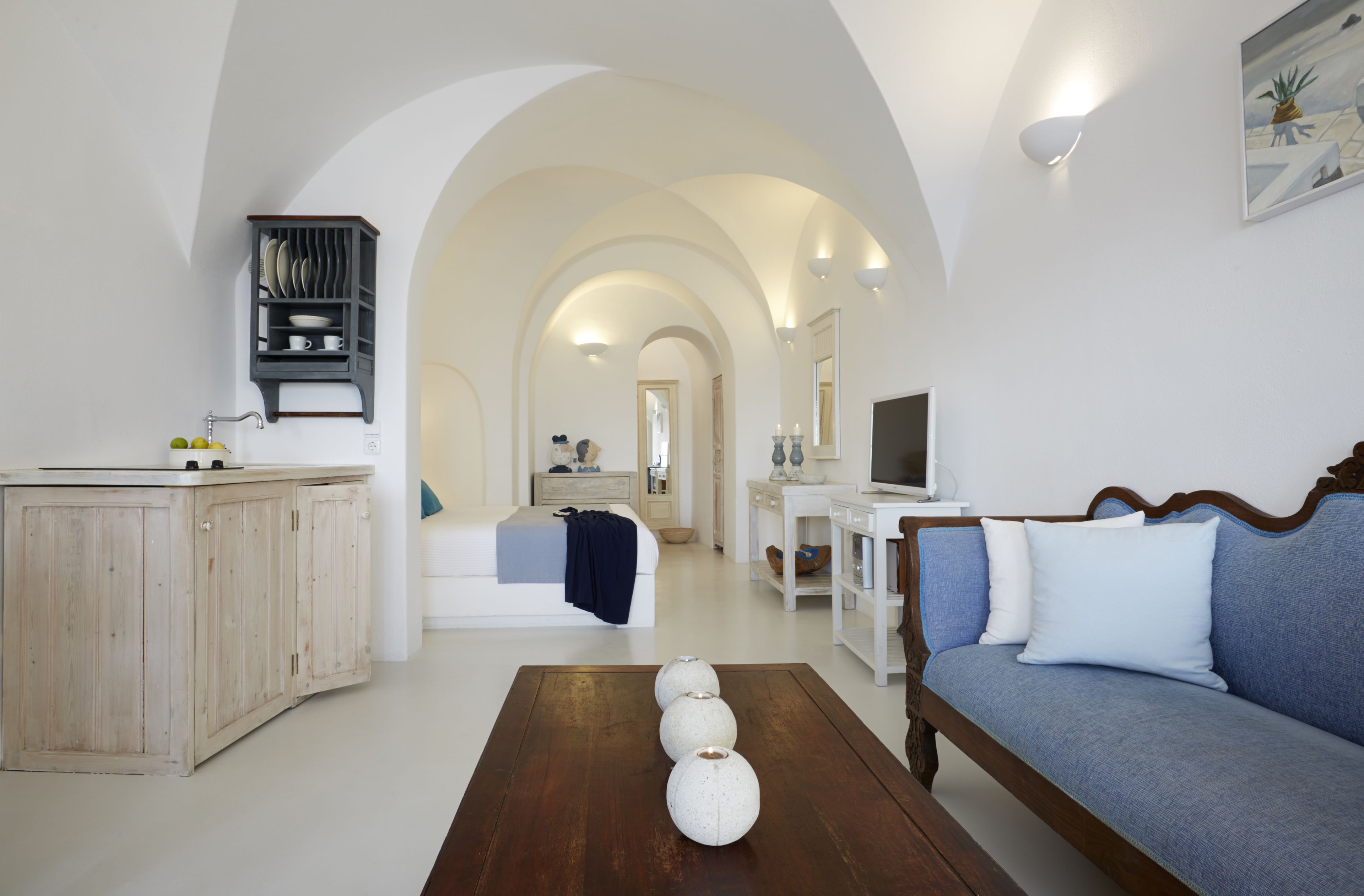Una sala de estar moderna con sofá, una mesa de centro y una zona de cocina con armarios y encimera.