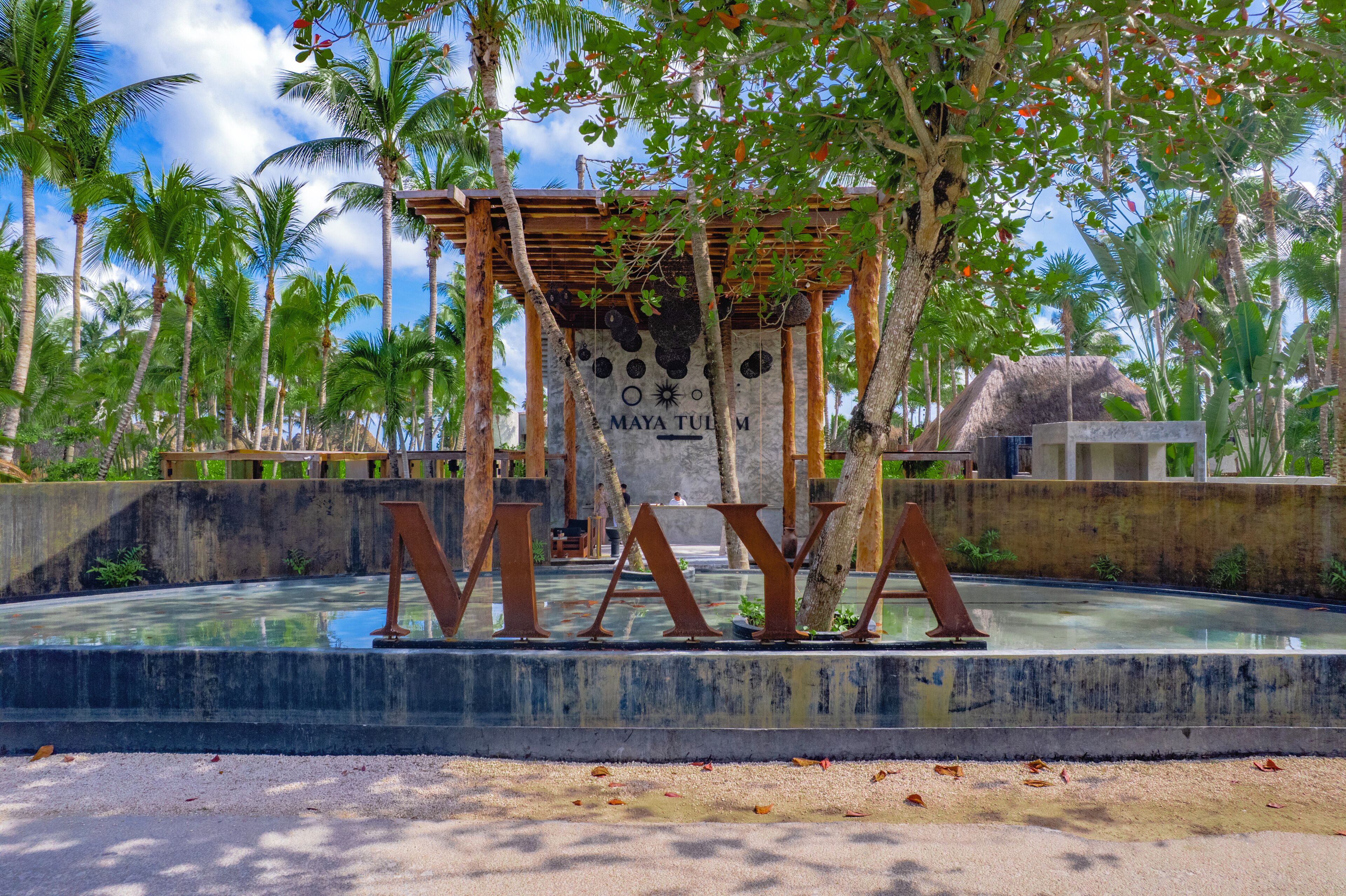 A tropical resort with a water feature and a structure with the word 'MAYA' prominently displayed.